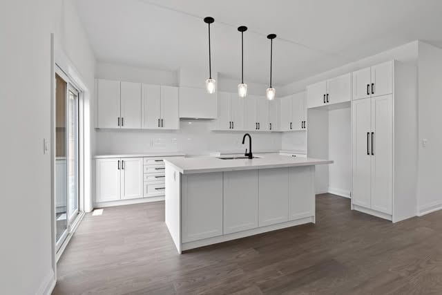 Modern white kitchen renovation with large island and pendant lighting in Brampton